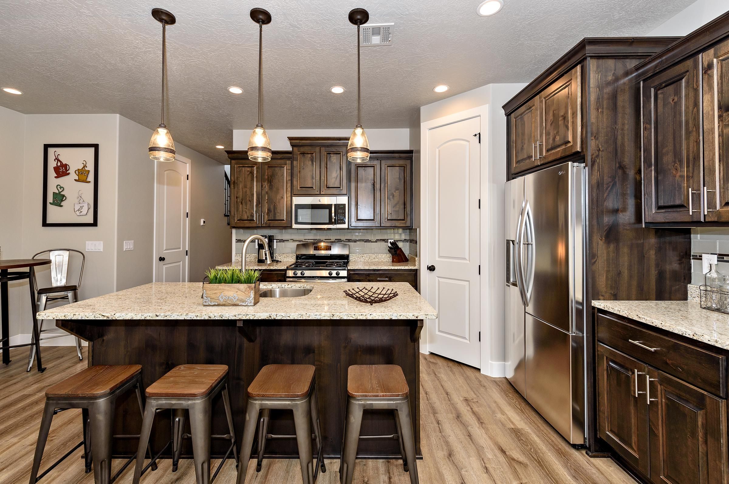 A modern kitchen with dark wood cabinets, stainless steel appliances, and a central island with stools.