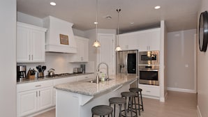 A modern kitchen with white cabinetry, stainless steel appliances, and a granite countertop.