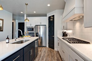 A modern kitchen with a stainless steel refrigerator, a double sink, and a gas stove. - Red Rock Peace (St. George)