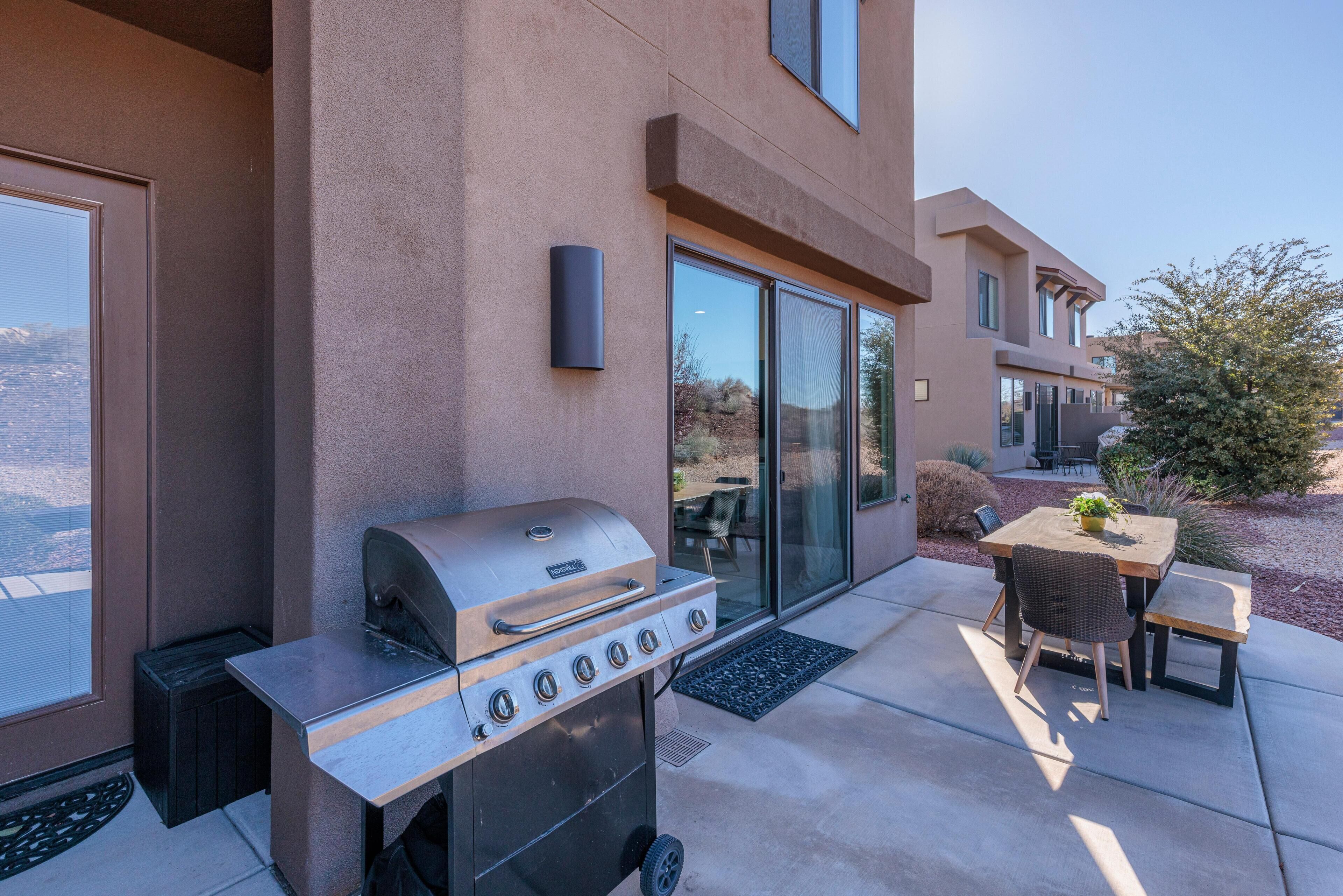 A patio with a grill, a table, and chairs.