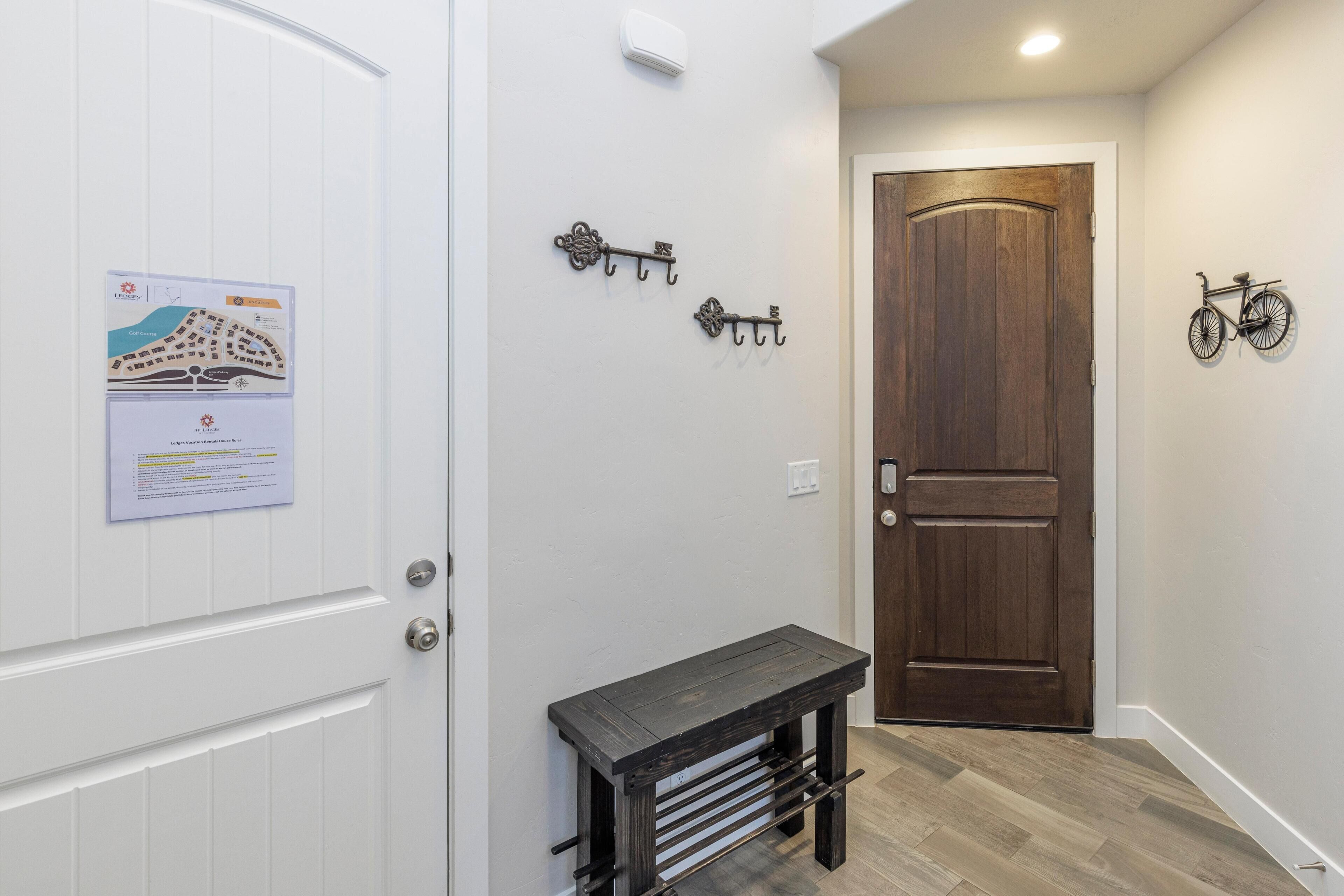 A hallway with a wooden door, a wall-mounted bicycle, and a bench.