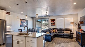 A modern kitchen with white cabinetry, a central island, and pendant lighting. - Base Camp (St. George)