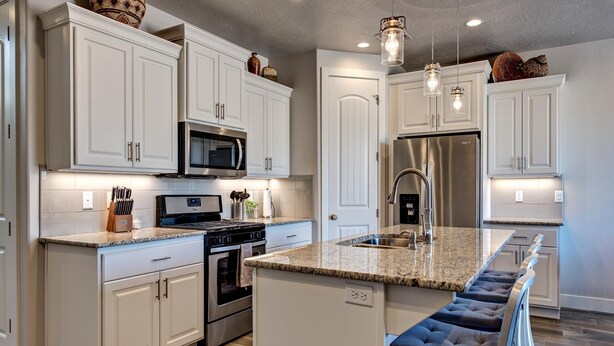A modern kitchen with white cabinetry, stainless steel appliances, and a granite countertop. - Base Camp (St. George)