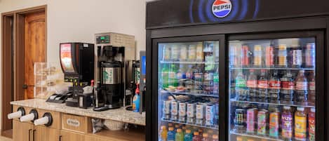 Una máquina expendedora con el logotipo de Pepsi, una máquina de café y un cubo de basura con la etiqueta 'B TRASH'.