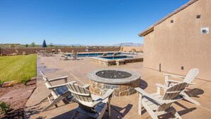 A patio area with Adirondack chairs, a stone fire pit, and a swimming pool. - Fairways Escape (St. George)