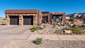 A modern house with two garages, a patio, and a landscaped garden. - Fairways Escape (St. George)