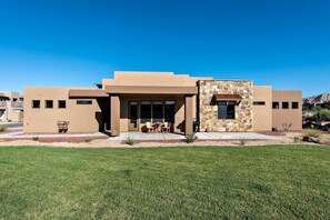 A modern building with a flat roof, large windows, and a stone accent wall. - Back Nine Villa (St. George)