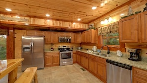 A wooden cabin-style kitchen with a refrigerator, stove, microwave, and dishwasher. - Paradise Point Pool Lodge Holiday home 6 (Sevierville)