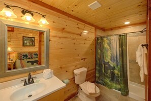 A wooden cabin bathroom with a sink, toilet, and shower curtain with a forest design. - Paradise Point Pool Lodge Holiday home 6 (Sevierville)