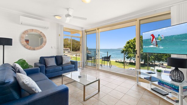 Una sala de estar moderna con un televisor grande, un sofá y vistas al mar.