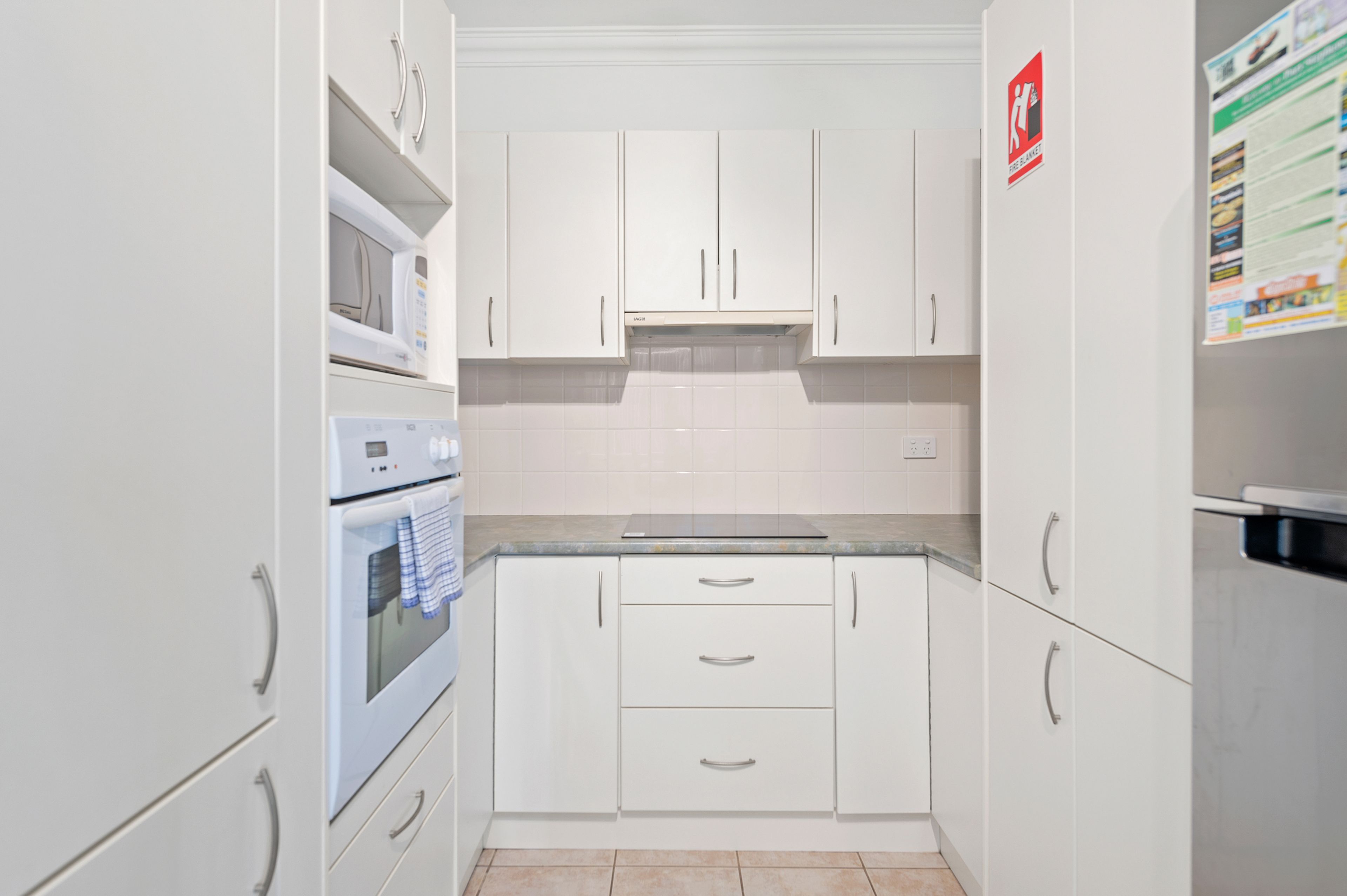 A kitchen with white cabinets, a microwave, and a stove.