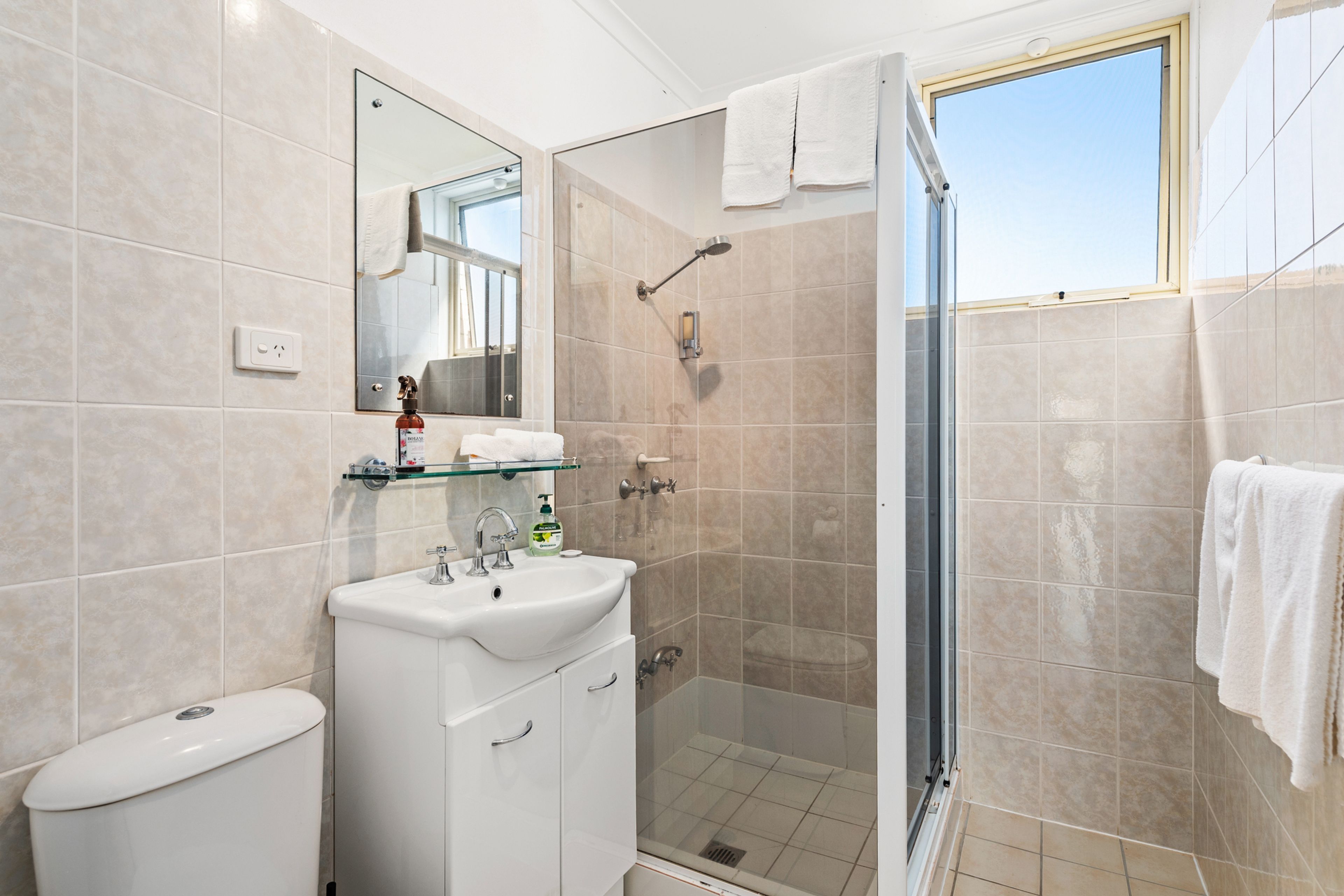 A modern bathroom with a glass shower enclosure, a white sink, and a toilet.