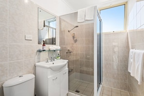 Une salle de bain moderne avec une douche à parois de verre, un lavabo blanc et des toilettes.