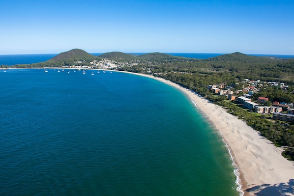 Vista aérea de una zona costera con playa, barcos y edificios.