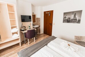 A hotel room with a bed, a desk with a chair, a wardrobe, a TV, a sink, and a door. - Hotel Restaurant Cala Luna (Marburg)