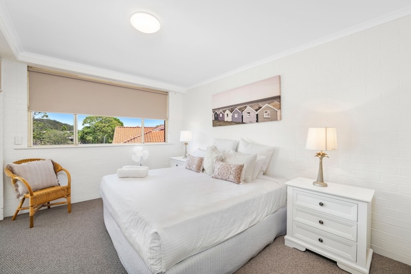 A bedroom with a large bed, a bedside table, a chair, a window with a view, and a wall-mounted picture. - Seaspray 3 close to Shoal Bay Beach (Nelson Bay)