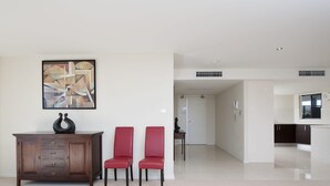 A modern living room with a wooden cabinet, two red chairs, and a contemporary abstract painting. - Dolphin Cove 13 Luxury Apartment in Nelson Bay (Nelson Bay)