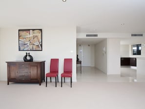 Een moderne woonkamer met een houten kast, twee rode fauteuils en een eigentijds abstract schilderij.