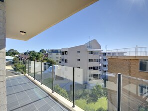 A modern building with a balcony, glass railings, and a clear view of the surrounding neighborhood. - Dolphin Cove 13 Luxury Apartment in Nelson Bay (Nelson Bay)