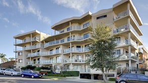 A multi-story residential building with balconies, a parking area, and a clear sky. - Dolphin Cove 13 Luxury Apartment in Nelson Bay (Nelson Bay)
