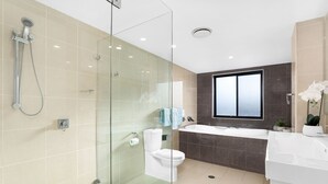 A modern bathroom with a glass-enclosed shower, a toilet, a bathtub, and a large window. - Dolphin Cove 13 Luxury Apartment in Nelson Bay (Nelson Bay)