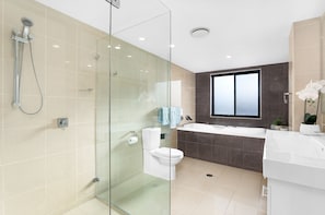 Een moderne badkamer met een douchecabine, een toilet, een bad en een groot raam.