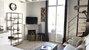 Un soggiorno moderno con camino, televisione e una scala.