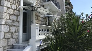 Un edificio in pietra con un balcone, una porta e una ringhiera, tutti di colore bianco.