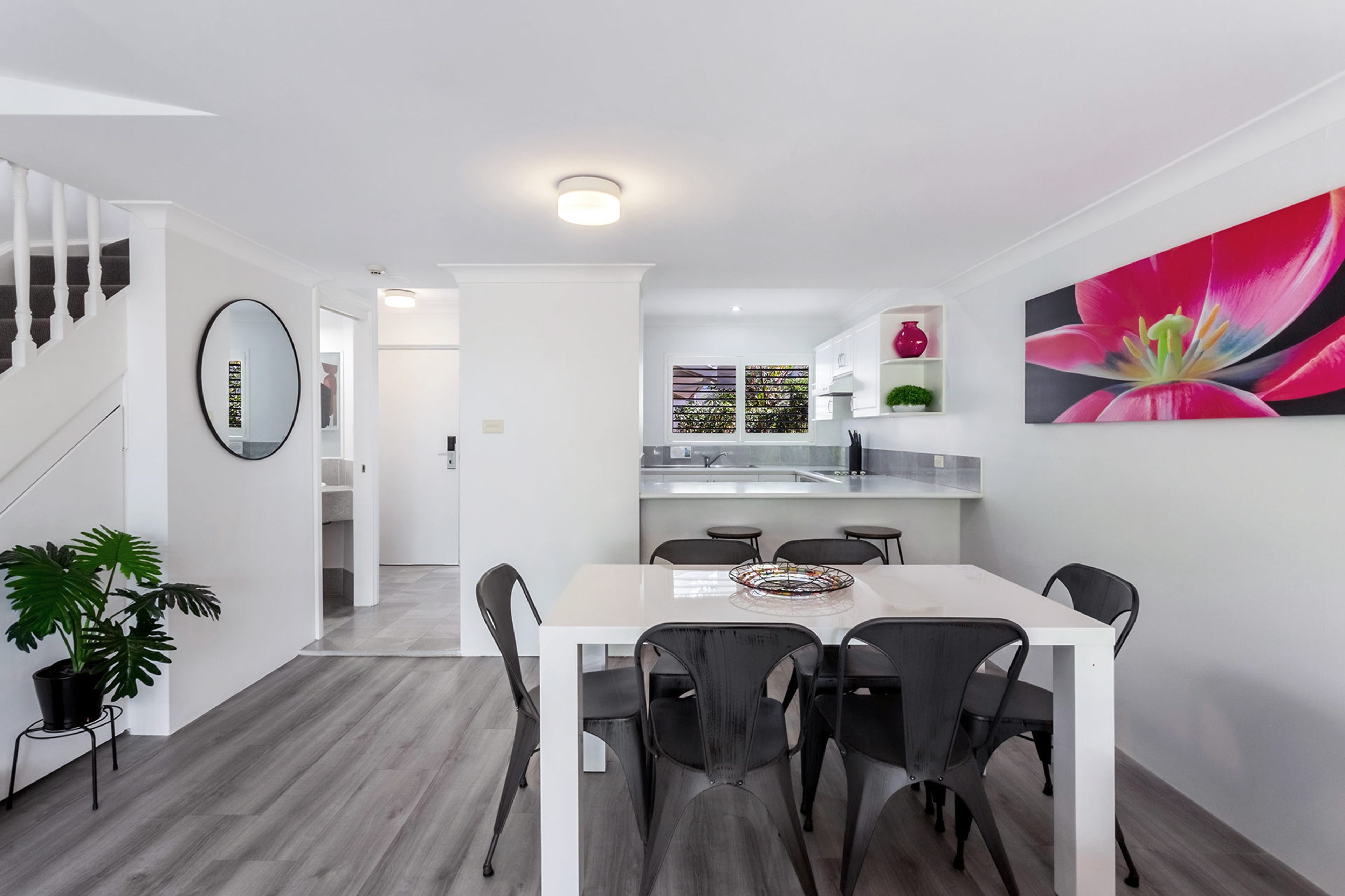 Et moderne interiør med spiseområde, køkken og trappe.