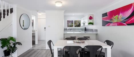 Un interior moderno con comedor, cocina y escalera.