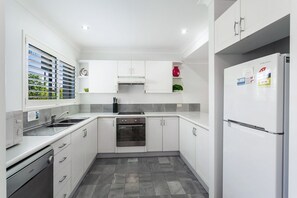 A modern kitchen with white cabinetry, a built-in oven, a stainless steel sink, and a Samsung refrigerator.
