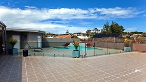A rooftop pool area with a clear view of the surrounding neighborhood, including houses and trees.