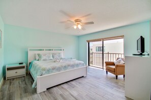 Un dormitorio con cama, mesita de noche, silla y balcón con vistas.