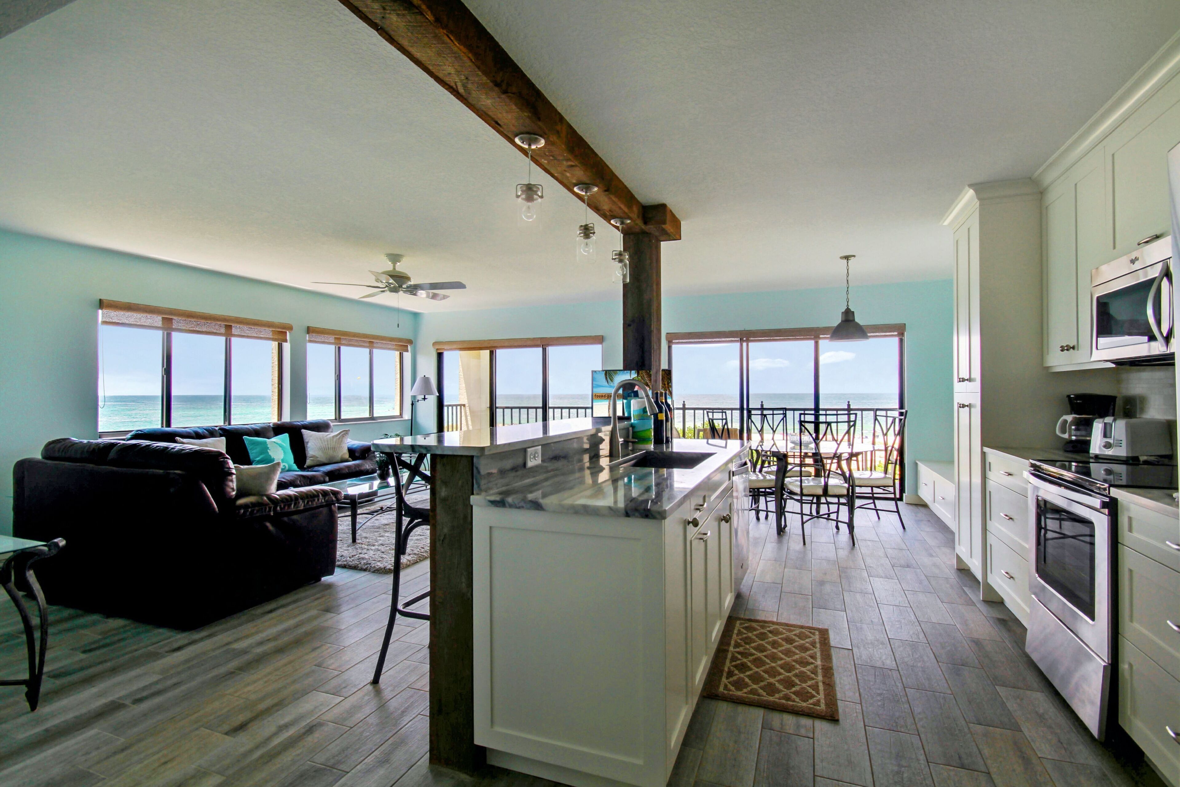 A spacious kitchen with a large island, white cabinets, and a view of the ocean.