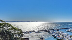 A marina with boats docked, a clear sky, and distant hills. - Right in Nelson Bay with views over the Marina (Nelson Bay)