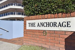 A sign with the text 'THE ANCHORAGE' and the number '9' on a brick wall.