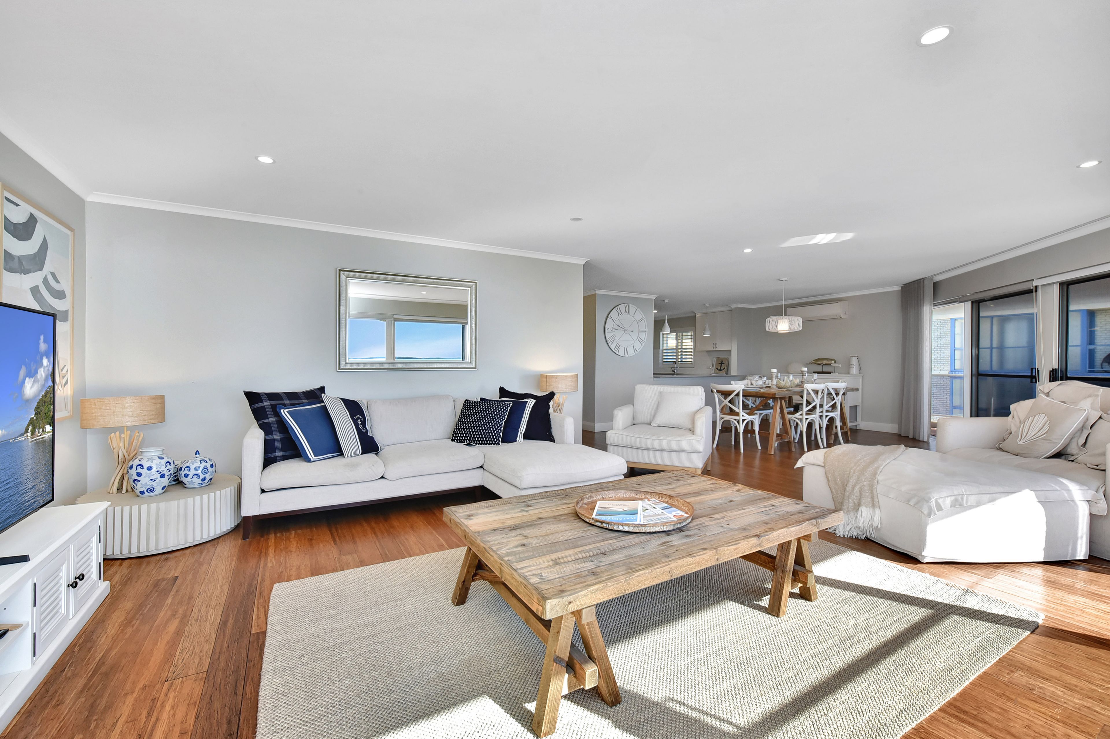A modern living room with a sofa, coffee table, and a dining area with chairs and a table.