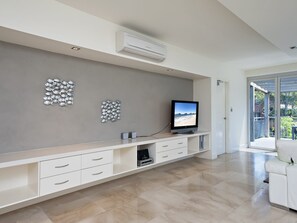 Ein modernes Wohnzimmer mit Flachbildfernseher, integrierter Klimaanlage und einer Wanddekoration mit Fischen.