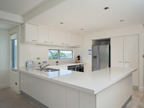 Eine moderne Küche mit weißen Schränken, einem Edelstahlkühlschrank und einer großen Kochinsel mit Spüle.
