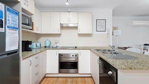 Eine moderne Küche mit weißen Schränken, Edelstahlgeräten, einer Arbeitsplatte aus Granit und Holzboden.
