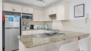 Eine moderne Küche mit Granit Arbeitsplatten, Edelstahlgeräten und weißen Schränken.