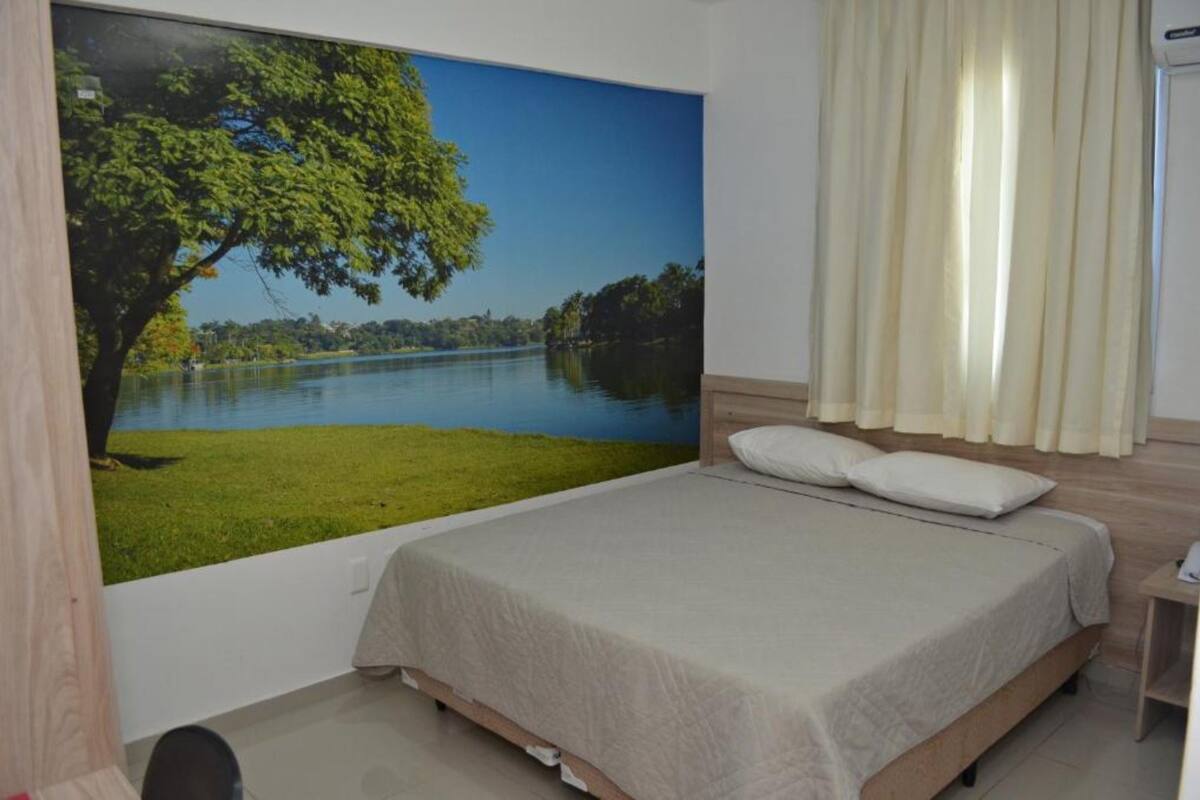 A bedroom with a large bed, a view of a lake, and a curtain.