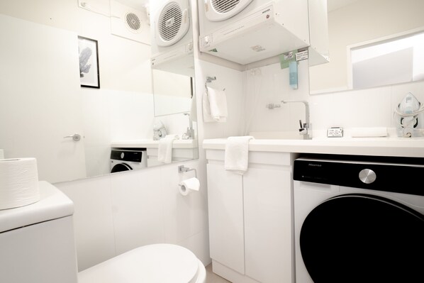 Un baño moderno con inodoro, lavamanos y lavadora.