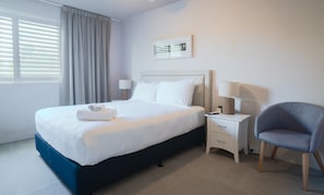 Een hotelkamer met een bed, nachtkastjes, een stoel en een raam met gordijnen.