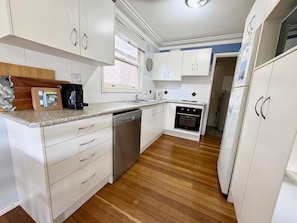 A kitchen with white cabinets, a dishwasher, a stove, and a refrigerator.