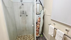 Eine Dusche mit Glastür, Handtuchhalter und Spiegel.