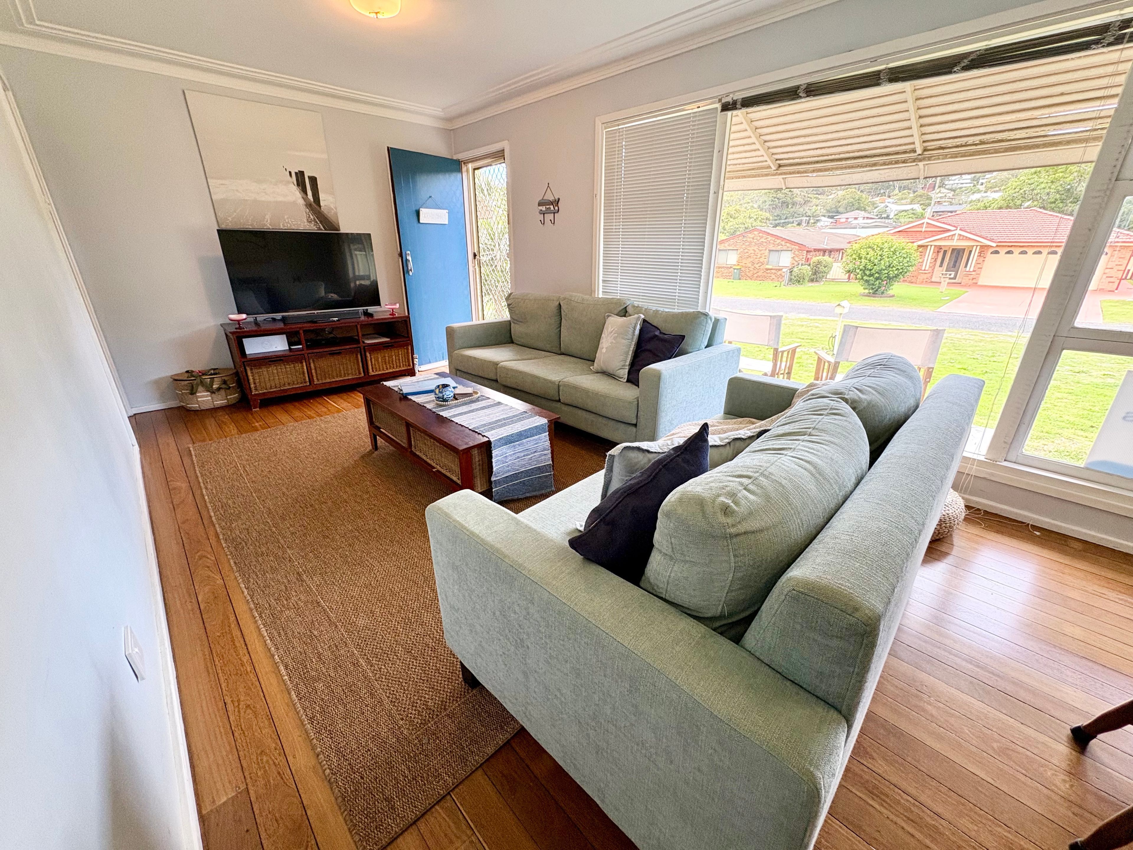 A living room with a television, two sofas, a coffee table, and a view of the outside.