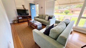 Ein Wohnzimmer mit einer Couch, einem Couchtisch, einem Fernseher und einem Bücherregal.