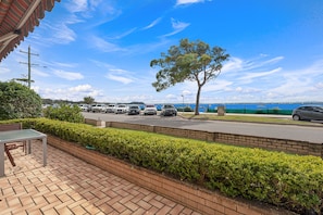 Uma área de estacionamento com carros, uma árvore e vista para o mar.