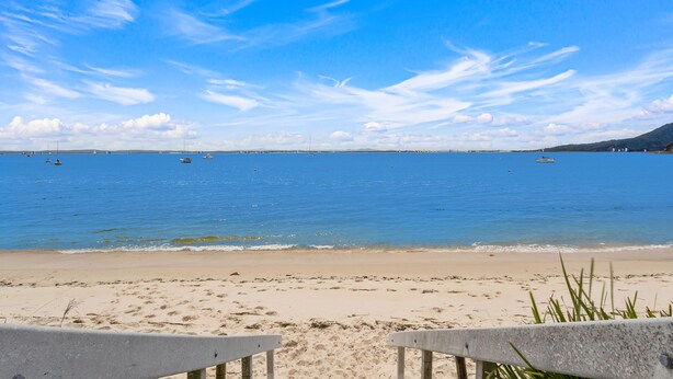 Een strand met heldere lucht, rustige zee en een zandstrand.